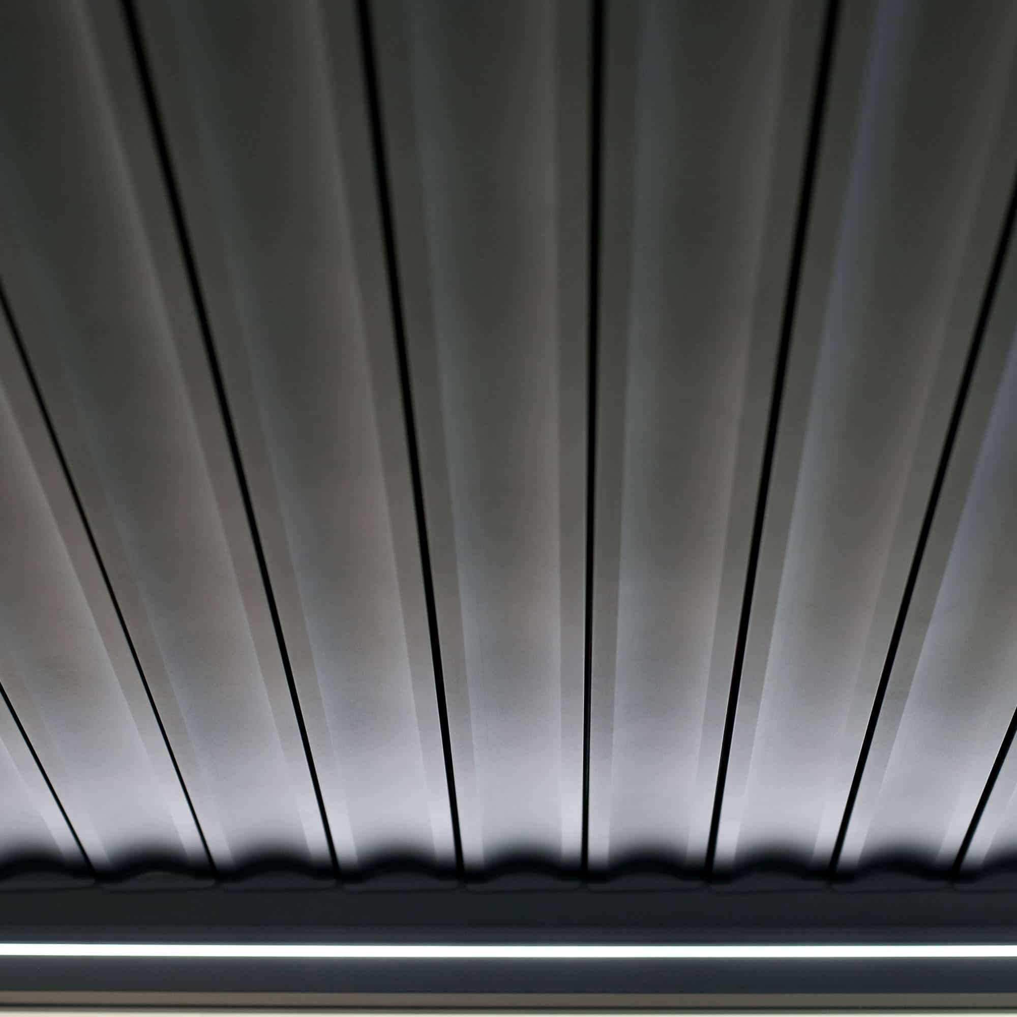 Die Pergola MotionFlex 300 von Wellis verfügt über einen Aluminiumrahmen in Mattanthrazit, elektrische Lamellen, eine integrierte LED-Beleuchtung und eine optionale Seitenbeschattung.